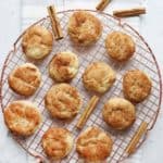 Soft chewy snickdoodles on a cooling rack with one cookie having a bite taken out of it